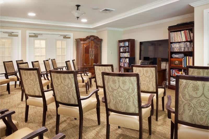 A well-organized conference room with rows of upholstered chairs facing a television and bookshelves.