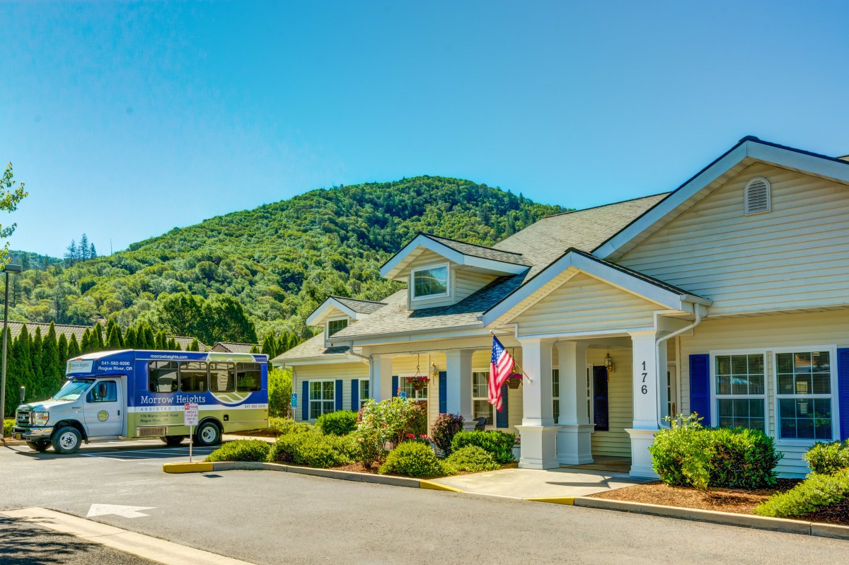 A sunny day view of a building with a mountainous backdrop and parked cars.