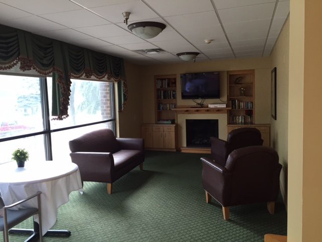 A cozy lounge area with comfortable chairs, a television, and a fireplace.