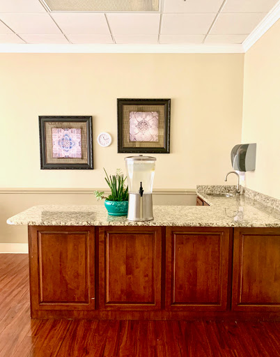 A stylish kitchenette featuring a granite countertop, decorative wall art, and a touch of greenery.