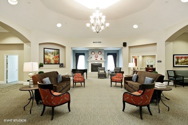 A spacious and elegantly decorated living room featuring a chandelier, multiple seating options, and a fireplace.