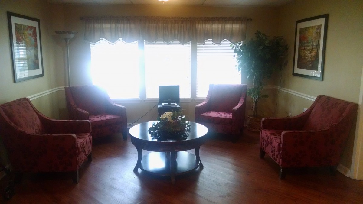 A cozy living room with red chairs and a central coffee table.