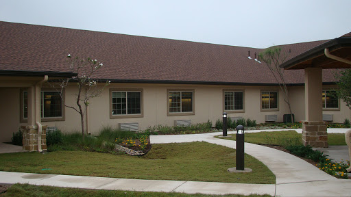 A single-story building surrounded by a landscaped area and a curved pathway.