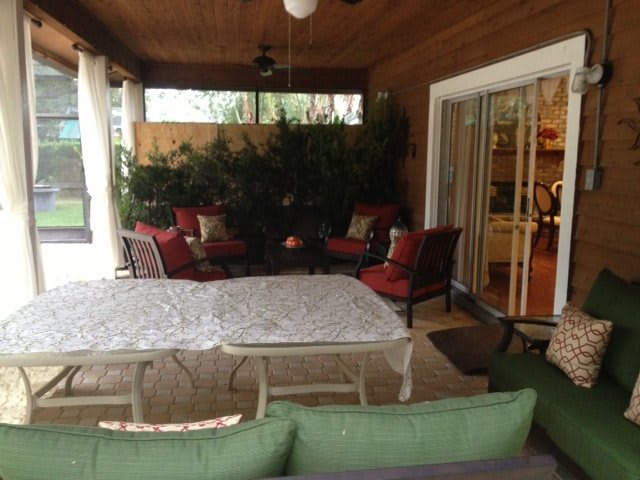 A cozy outdoor patio with red-cushioned seating and a large table under a covered roof.