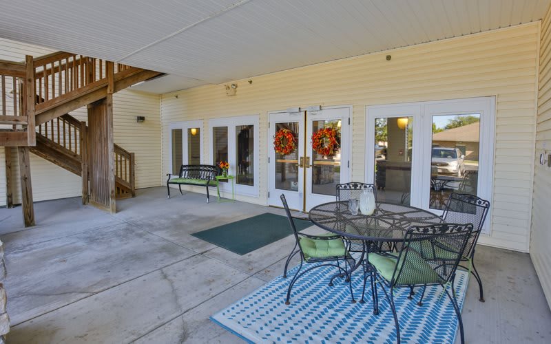 A cozy outdoor patio with a table and chairs, complete with decorative wreaths on the glass doors.