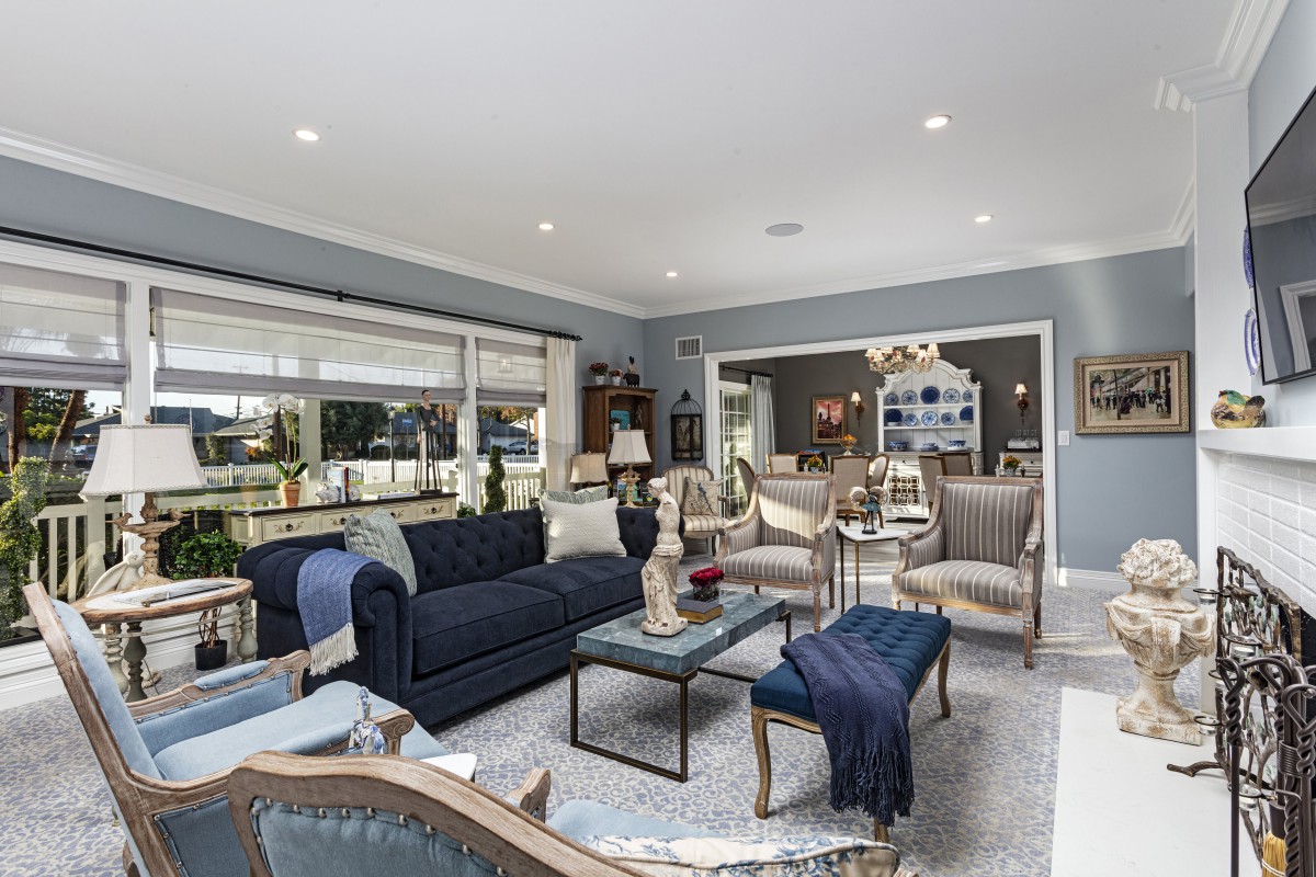A modern living room with stylish furniture, featuring a navy sofa, elegant chairs, and a large window providing natural light.