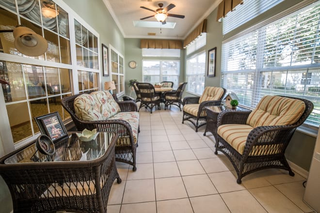 A bright sunroom with wicker furniture and large windows allowing natural light.