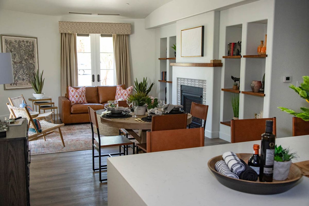 A modern living room featuring a dining table, sofa, and fireplace with surrounding shelves.