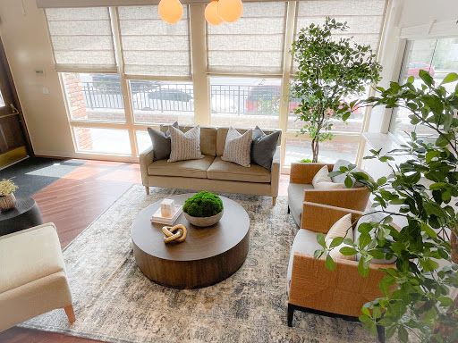 A cozy and stylish living room featuring a comfortable sofa, two armchairs, and a round coffee table, adorned with decorative plants.