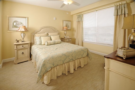 A cozy bedroom with a neatly made bed, bedside tables with lamps, and soft lighting.