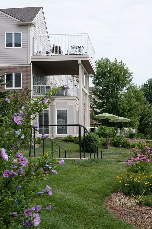 A scenic garden with blooming flowers and a view of a residential building with balconies and outdoor seating.