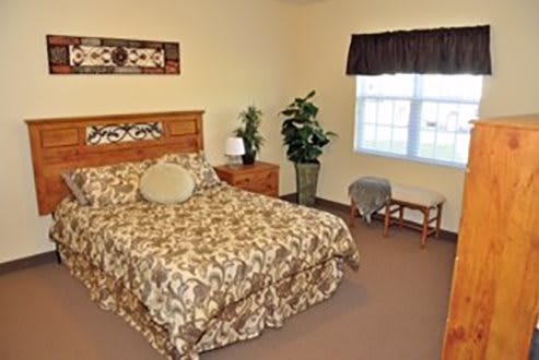 A cozy bedroom with a bed, nightstand, and decorative plants.
