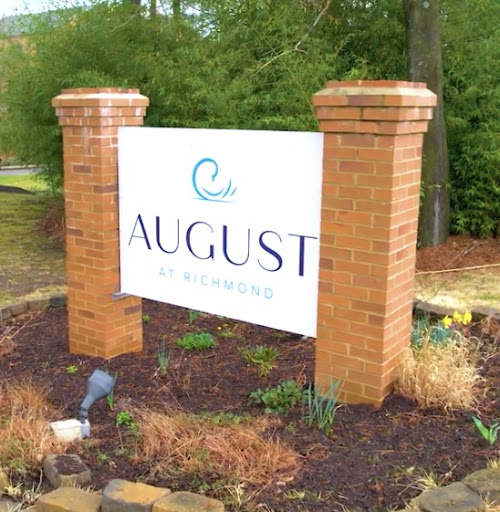 Entrance sign for a place named 'August' with decorative landscaping.