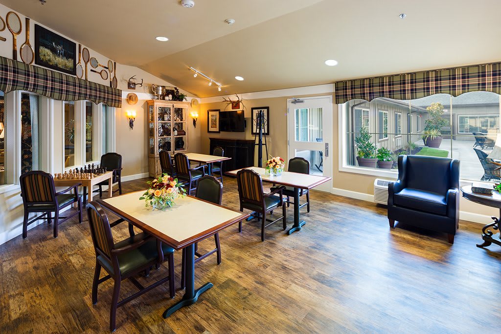 A cozy living room area with tables, chairs, and a fireplace.