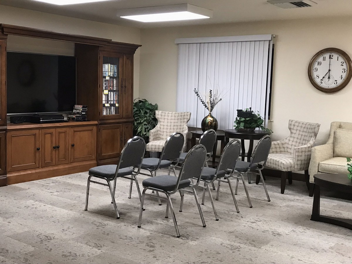 A small meeting room arranged with chairs facing a wooden cabinet and a decorative setup.