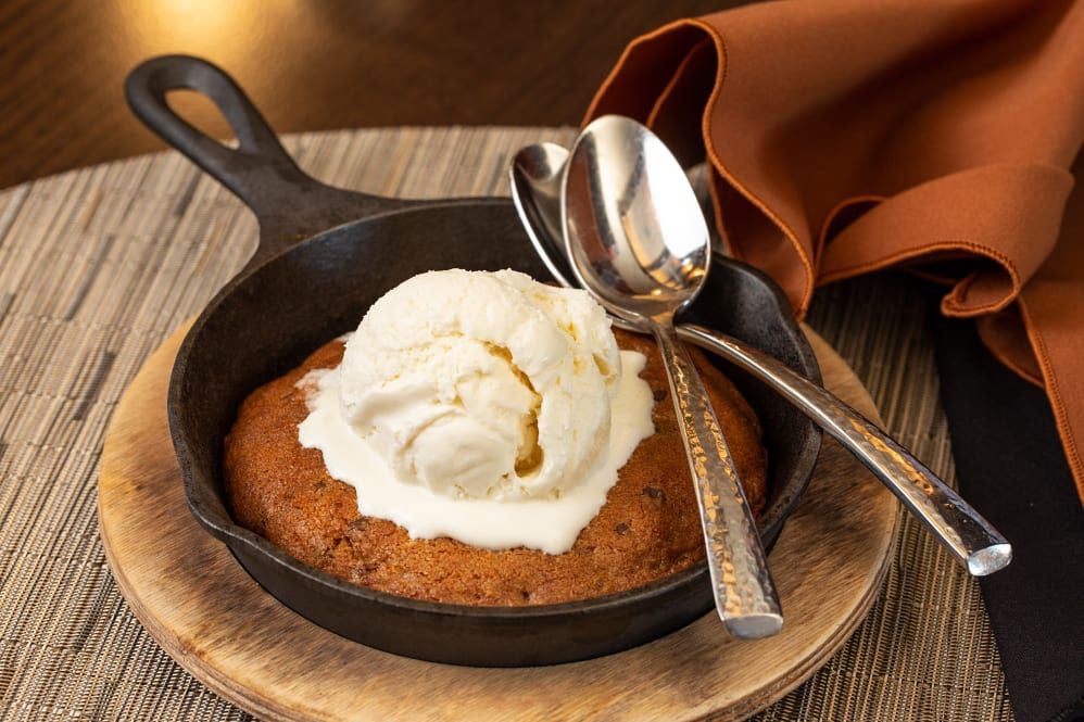 A warm chocolate chip skillet cookie topped with vanilla ice cream.