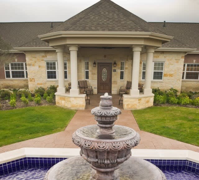 A charming house with a prominent fountain and landscaped entrance.