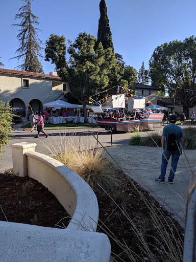 A lively outdoor event with people enjoying the atmosphere surrounded by trees and buildings.