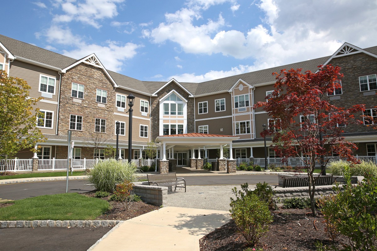 A residential building with neatly landscaped grounds and a clear blue sky.