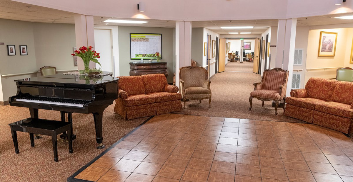 A cozy lobby with a piano and seating area leading to a hallway.