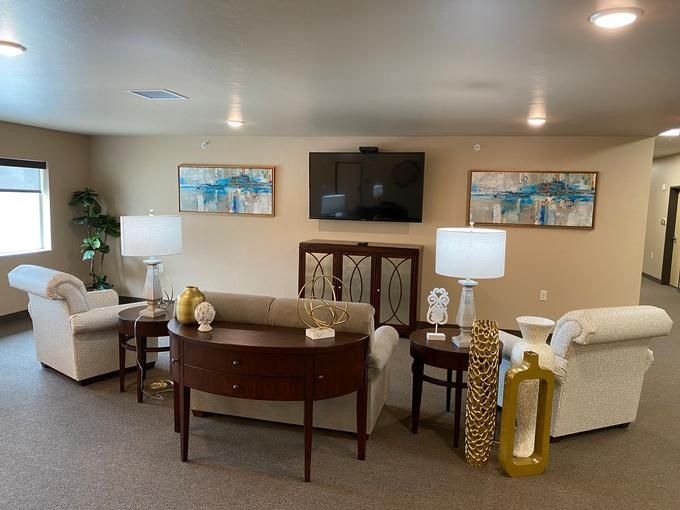 A cozy living room with comfortable seating, lamps, a coffee table, and decorative artwork.