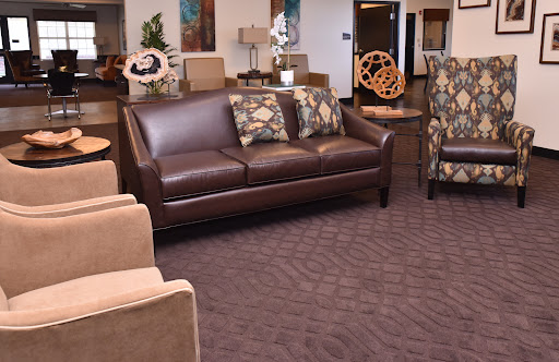 A stylish lounge area featuring a brown leather sofa and patterned armchairs.