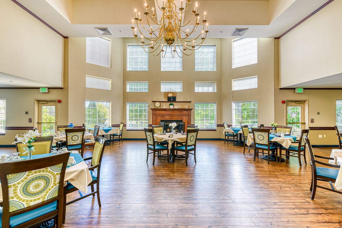 A spacious and elegant restaurant dining area with large windows and a central chandelier.