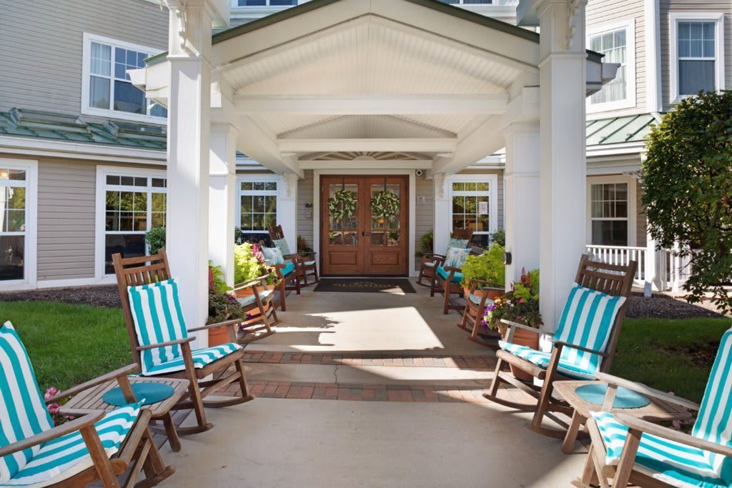 A welcoming entrance with striped-cushioned rocking chairs and potted plants on the porch.