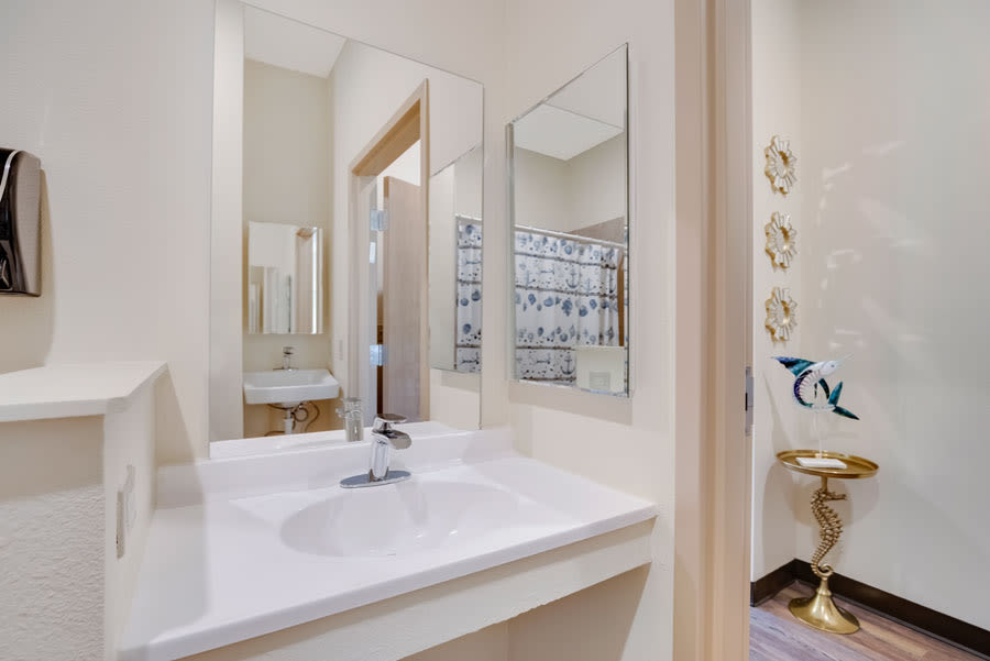 A clean and modern bathroom featuring a sink with a sleek faucet and two mirrors.