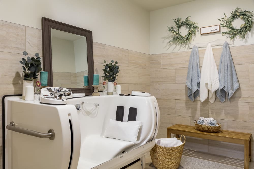 A modern bathroom featuring a luxury walk-in bathtub, a mirror, and tasteful decor with plants and towels.