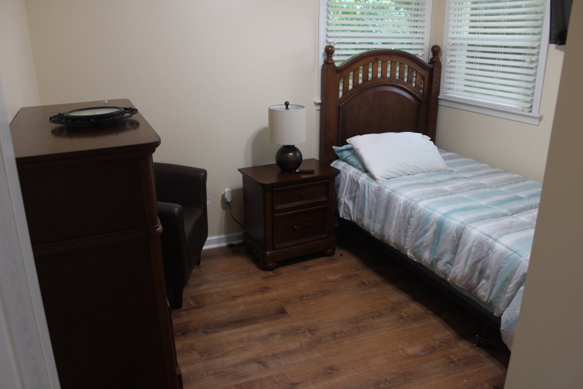 A cozy bedroom with a single bed, nightstand, and armchair.