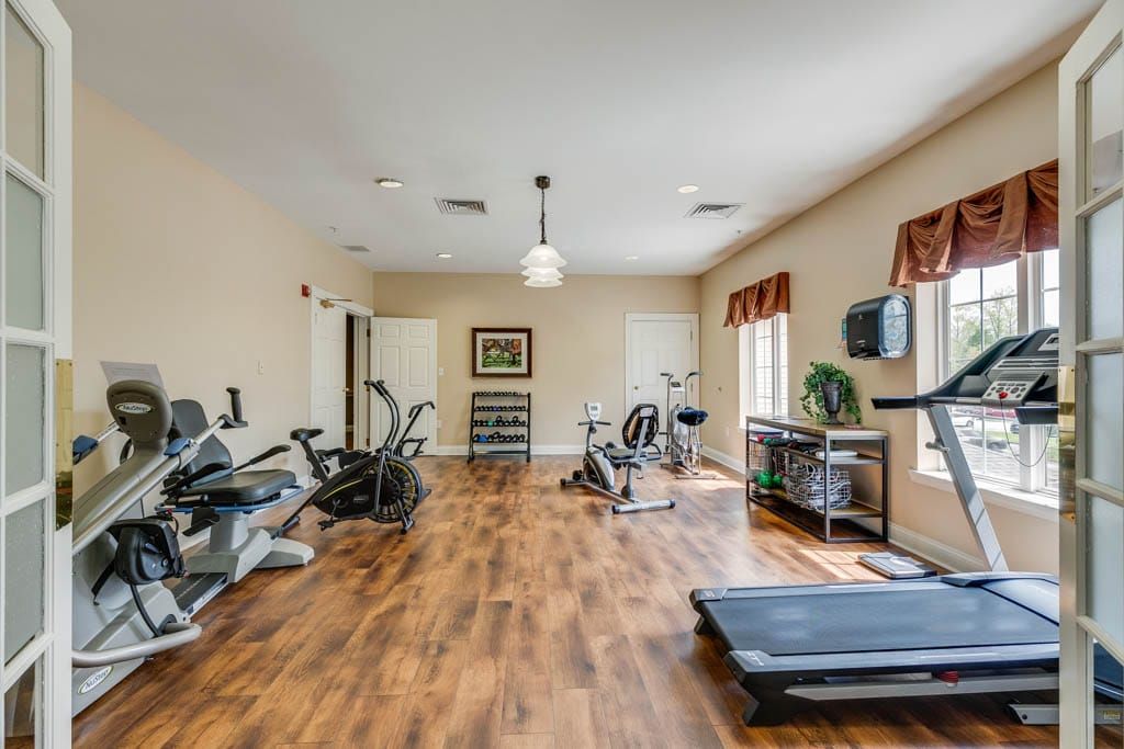 A well-lit gym with various exercise equipment, including treadmills and stationary bikes.