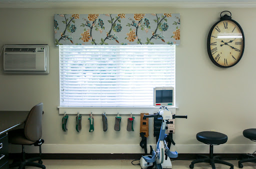 A well-lit interior space featuring a window adorned with floral valance and exercise equipment arranged nearby.