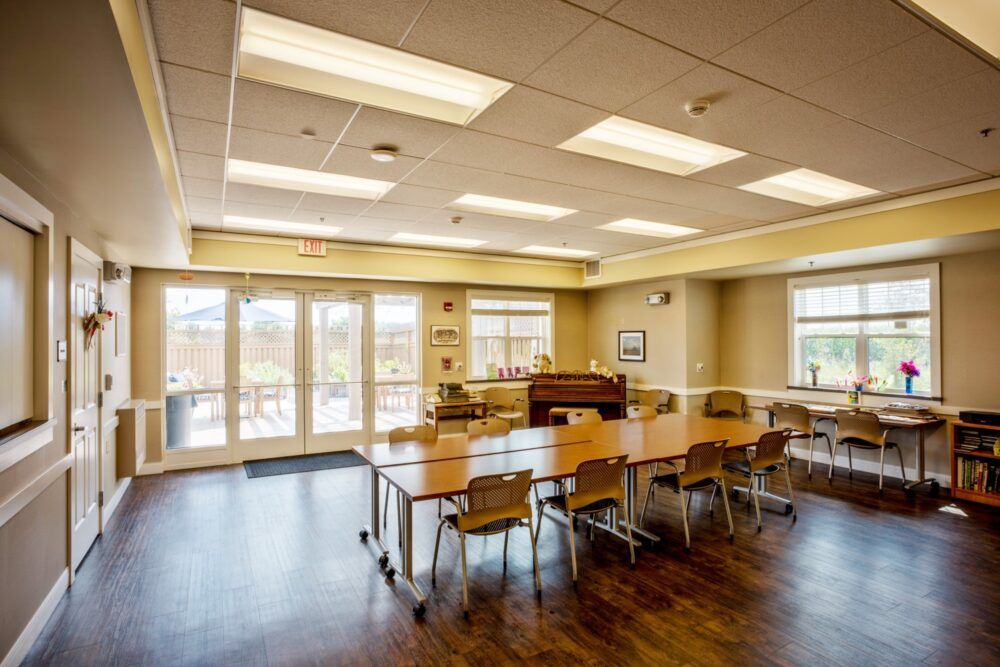 A bright and spacious conference room with tables and chairs, featuring large windows and a wooden floor.