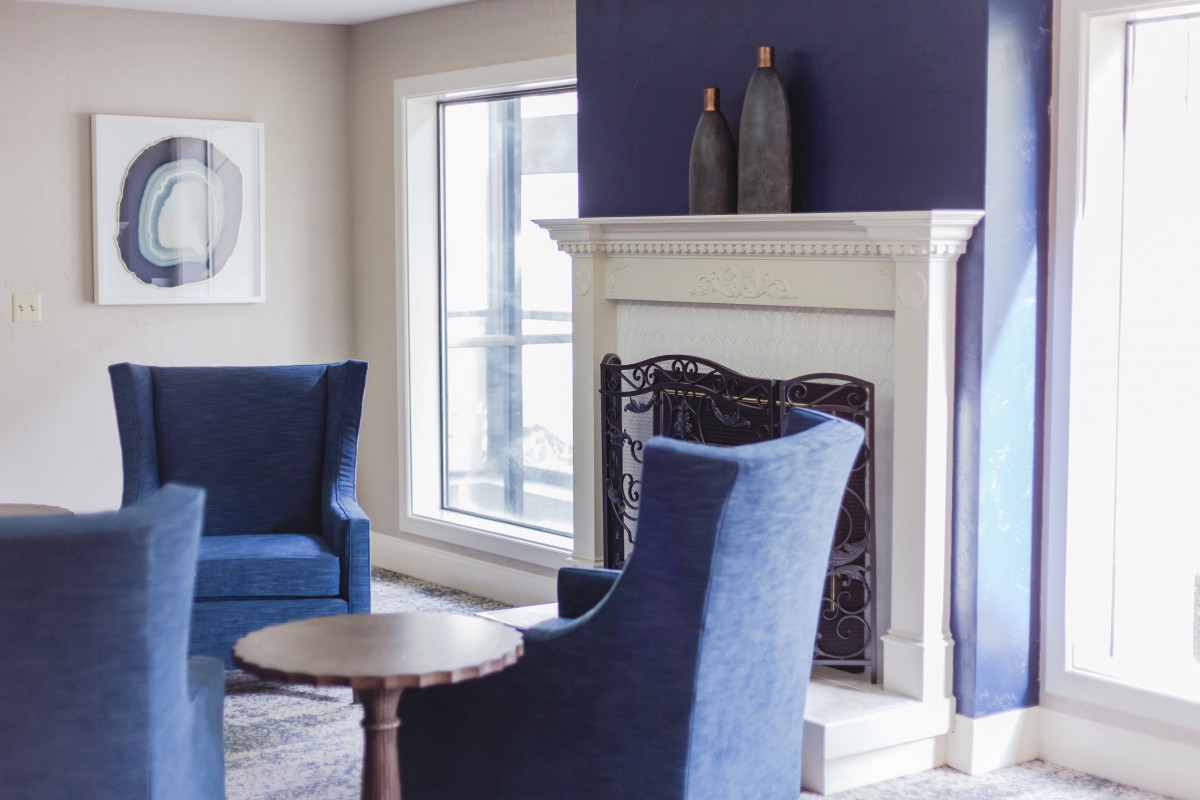 A modern living room with blue chairs, a fireplace, and elegant decor.