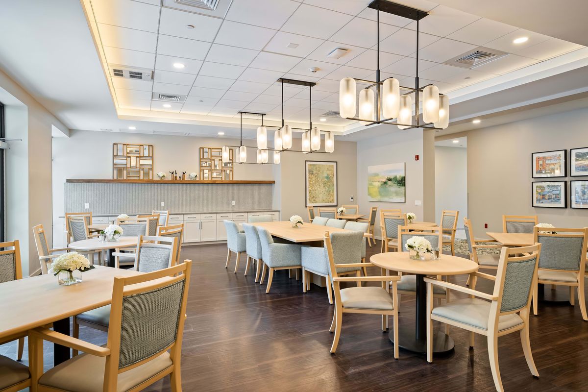 A modern dining room with neatly arranged tables and chairs, featuring contemporary lighting fixtures.