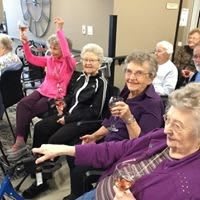 A group of elderly individuals enjoying a social gathering, smiling and raising glasses in celebration.