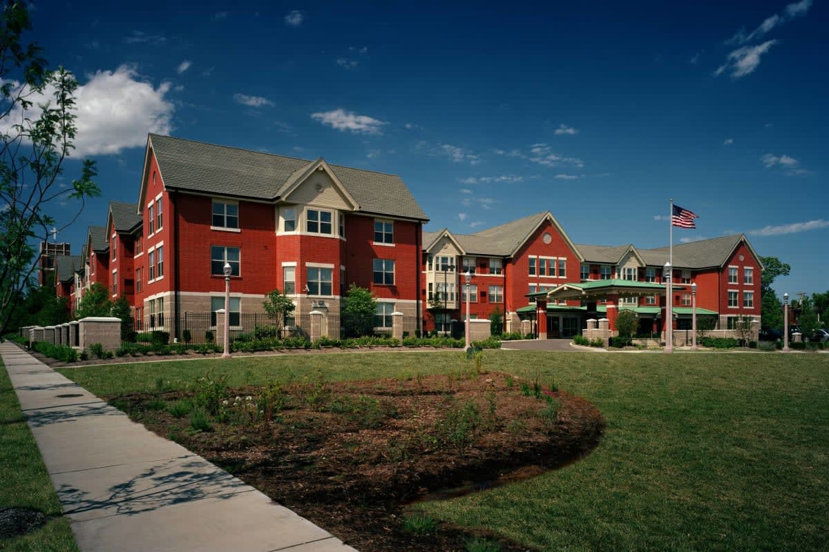 A large red-brick building with a well-maintained lawn and clear blue sky.