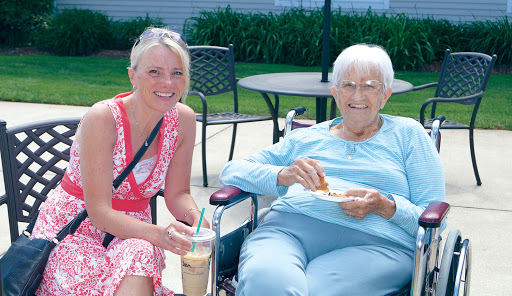 A joyful moment shared between a younger and an elderly woman enjoying food and drinks outdoors.