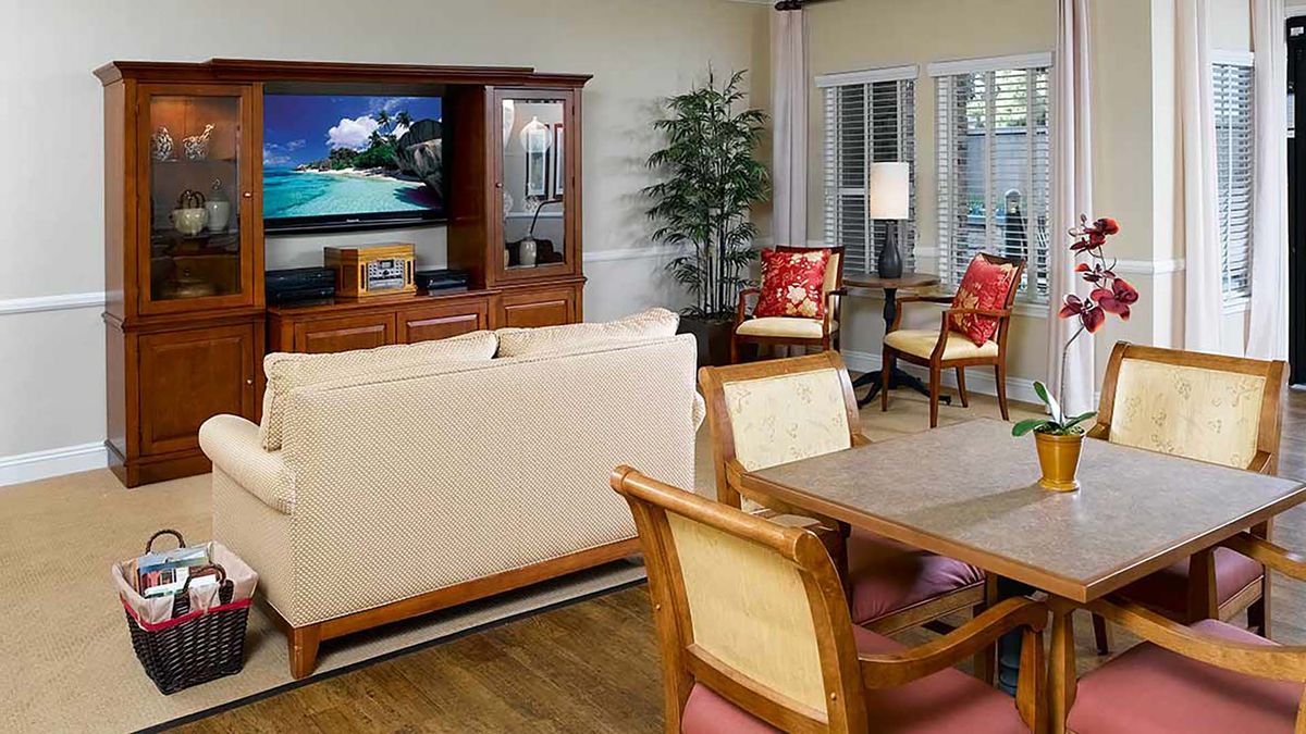 A cozy living room with a TV, sofa, dining table, and stylish wooden furniture.