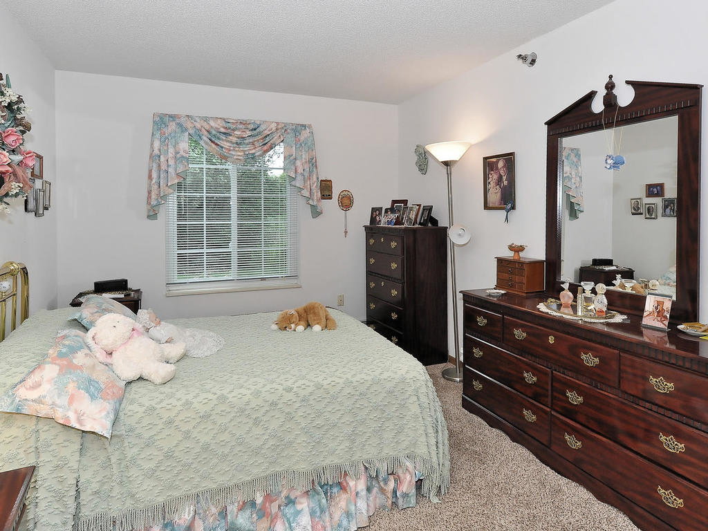 A cozy bedroom with a bed, dresser, and mirror, complemented by soft lighting and decor.