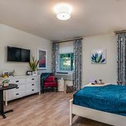 A modern bedroom with stylish decor, featuring a comfortable bed, wall-mounted TV, and elegant furniture.
