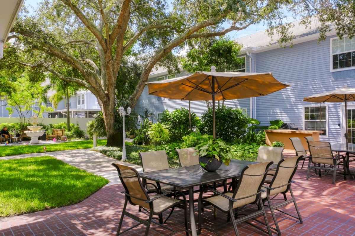 A serene outdoor seating area with a table, chairs, and umbrella set amidst lush greenery.