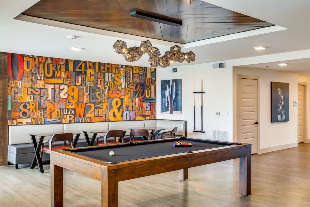 A modern game room featuring a stylish pool table, abstract artwork, and contemporary lighting.