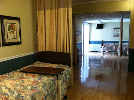 A well-lit hospital patient room featuring a bed and curtains for privacy.