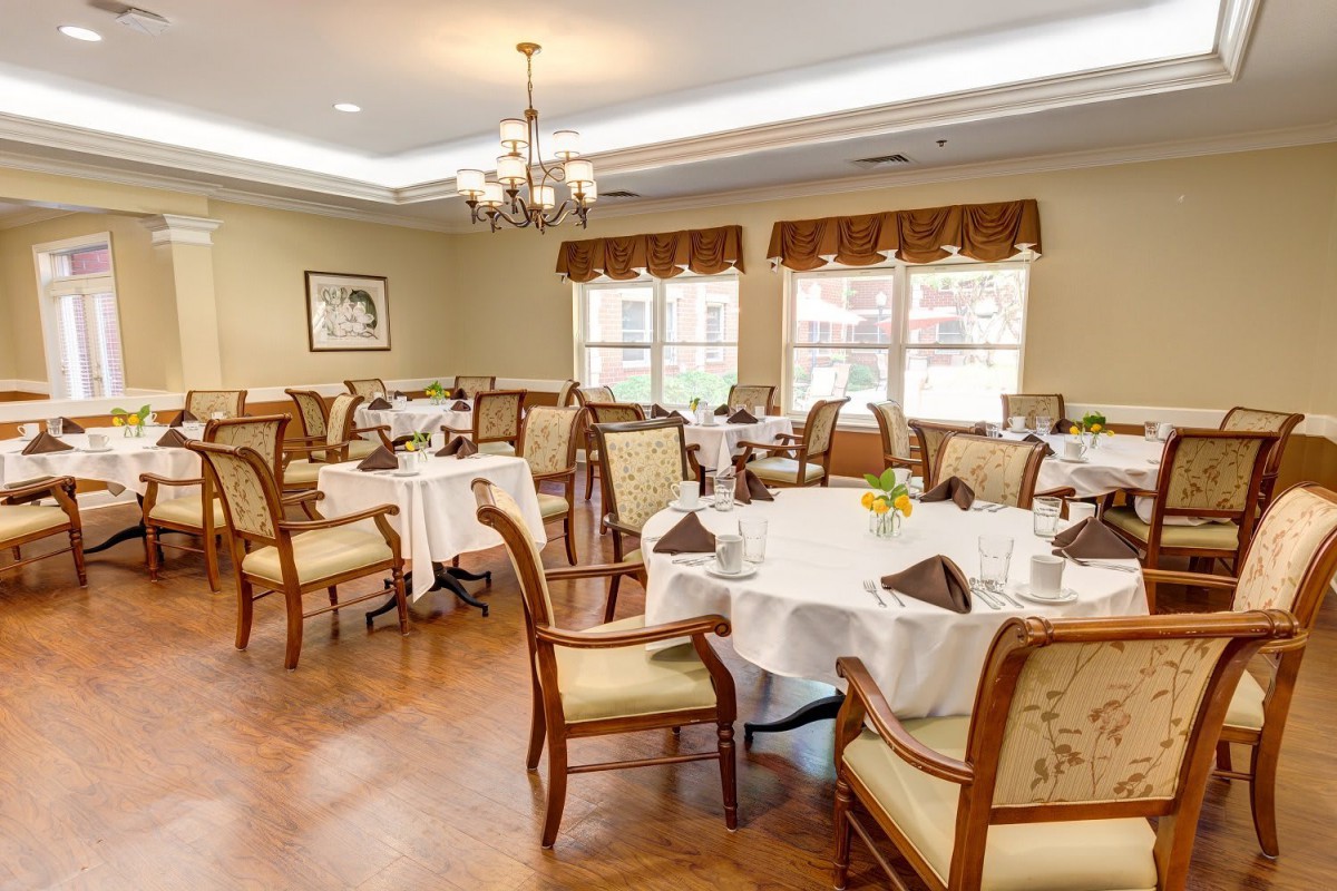 An elegant dining room with neatly arranged tables and chairs, featuring a chandelier and tasteful decor.