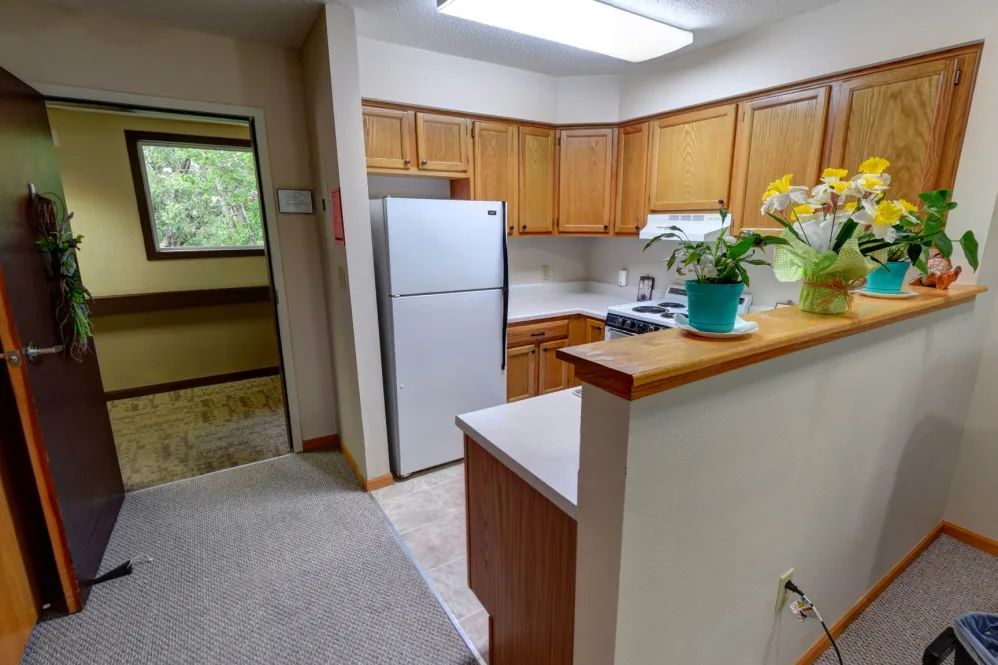 A modern apartment kitchen with wooden cabinets and stainless steel appliances.