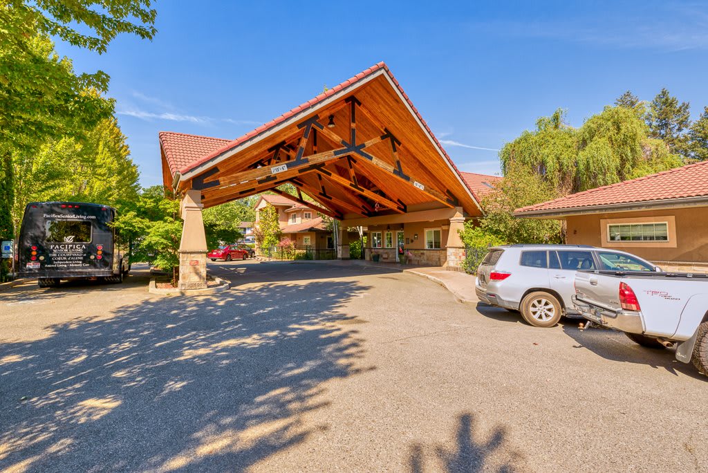 Entrance to a building with a covered driveway and parked cars.