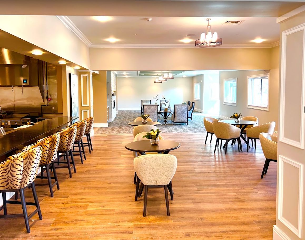 A spacious and well-lit dining area with wooden flooring, featuring neatly arranged tables and chairs.