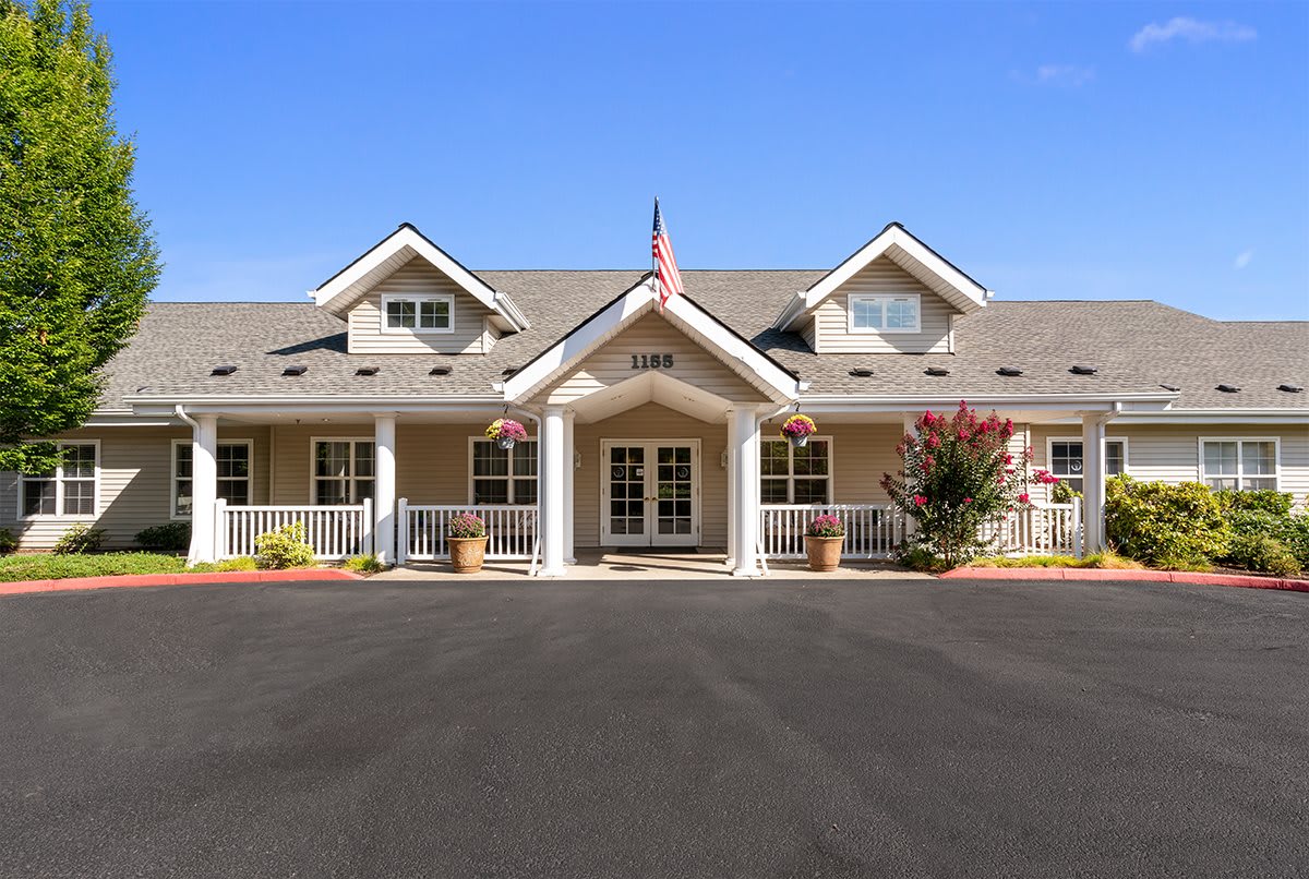 A spacious residential building with a well-maintained front yard and an American flag.